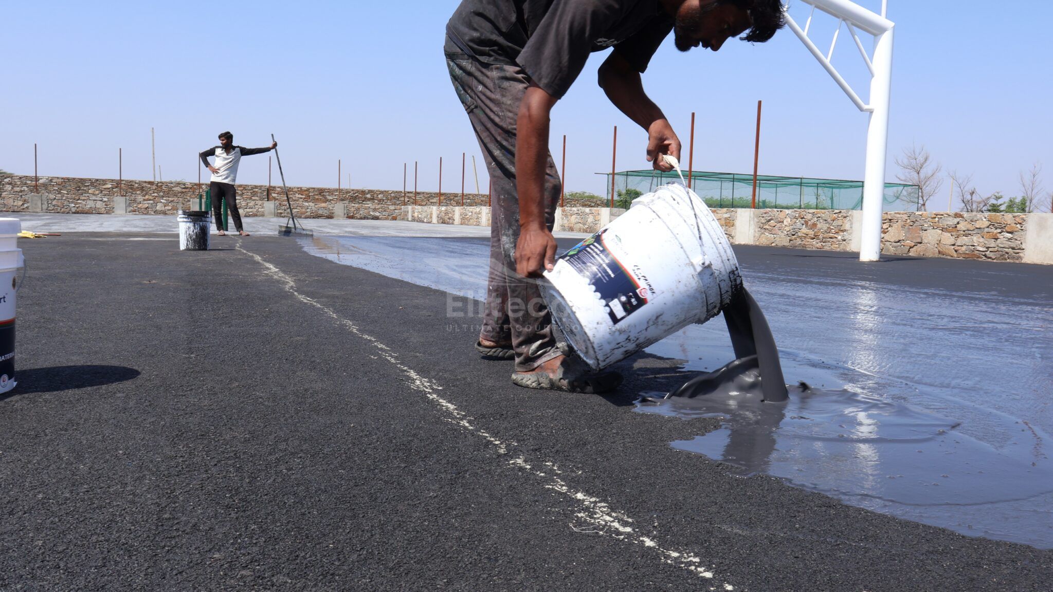 Waatti Contracting crew member applying SportMaster acrylic coating during sport court construction