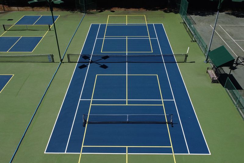Court-level view down the length of a resurfaced tennis court with blended lines