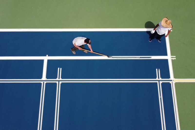 Crew taping and striping court lines from above