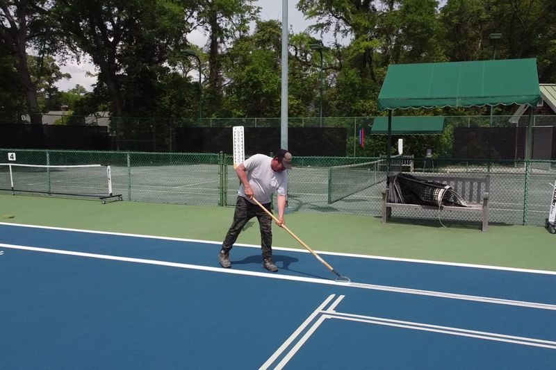 Crew member pulling a squeegee along a line on the new surface
