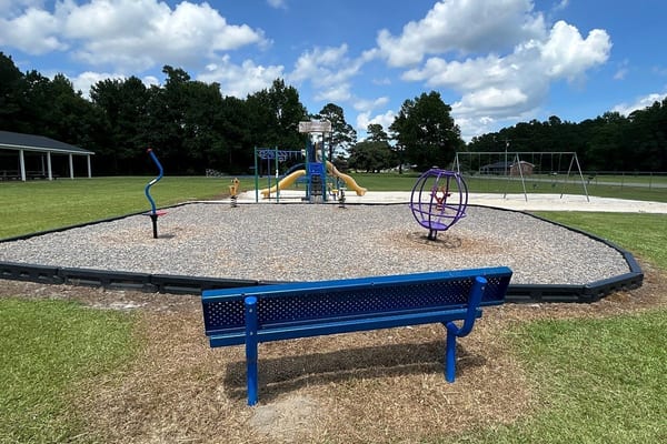 Park bench on a new concrete pad beside a playground, Sandyfield, NC