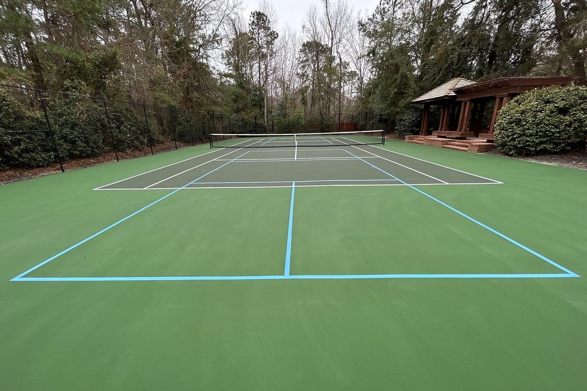 Resurfaced private tennis court with white tennis and light-blue pickleball lines, gazebo and pines behind — Wilmington, NC